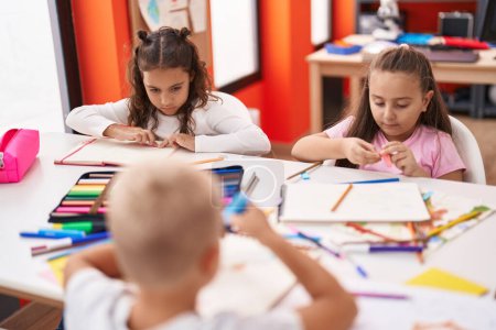 Photo for Group of kids preschool students sitting on table drawing on paper at classroom - Royalty Free Image