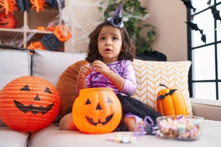 Téléchargez les photos : Adorable hispanic toddler having halloween party holding pumpkin toy at home - en image libre de droit