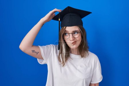 Photo for Blonde caucasian woman wearing graduation cap confuse and wonder about question. uncertain with doubt, thinking with hand on head. pensive concept. - Royalty Free Image