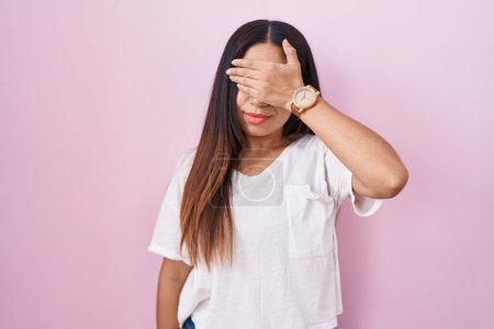 Téléchargez les photos : Young arab woman standing over pink background covering eyes with hand, looking serious and sad. sightless, hiding and rejection concept - en image libre de droit