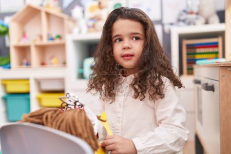 Photo for Adorable hispanic girl smiling confident playing with doll at kindergarten - Royalty Free Image