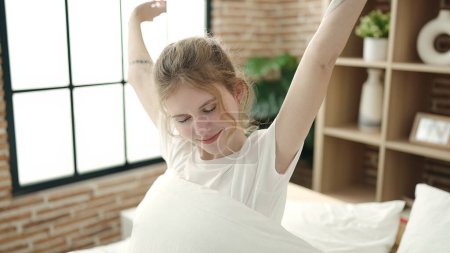 Téléchargez les photos : Jeune femme blonde se réveillant bras tendus dans la chambre - en image libre de droit