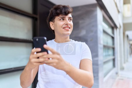 Téléchargez les photos : Non binary man smiling confident using smartphone at street - en image libre de droit