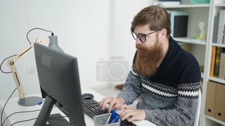 Téléchargez les photos : Young redhead man student using computer studying at library university - en image libre de droit
