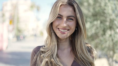 Téléchargez les photos : Jeune femme blonde souriante confiante debout au parc - en image libre de droit