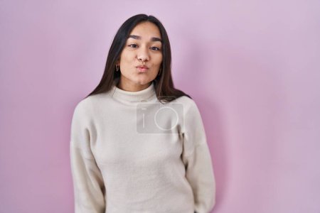 Photo for Young south asian woman standing over pink background looking at the camera blowing a kiss on air being lovely and sexy. love expression. - Royalty Free Image