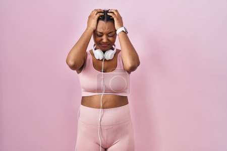 Photo for African american woman with braids wearing sportswear and headphones suffering from headache desperate and stressed because pain and migraine. hands on head. - Royalty Free Image