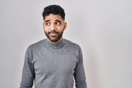 Foto de Hispanic man with beard standing over white background smiling looking to the side and staring away thinking. - Imagen libre de derechos
