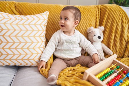 Foto de Adorable niño hispano jugando con ábaco sentado en el sofá en casa - Imagen libre de derechos