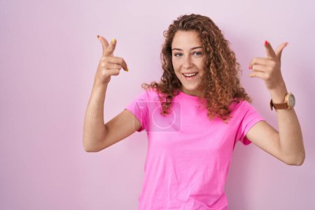 Photo for Young caucasian woman standing over pink background pointing fingers to camera with happy and funny face. good energy and vibes. - Royalty Free Image