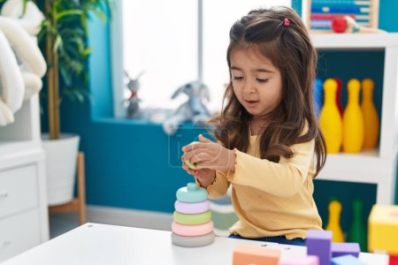 Photo for Adorable hispanic girl playing with construction blocks sitting on table at kindergarten - Royalty Free Image