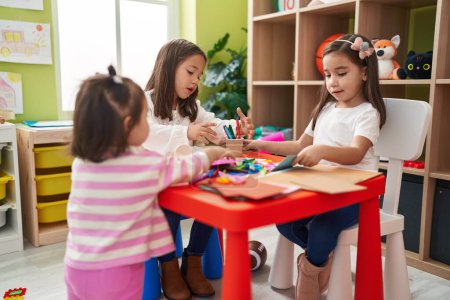 Foto de Grupo de niños estudiantes de preescolar sentados en el dibujo de la mesa y hacer manualidades en el jardín de infantes - Imagen libre de derechos