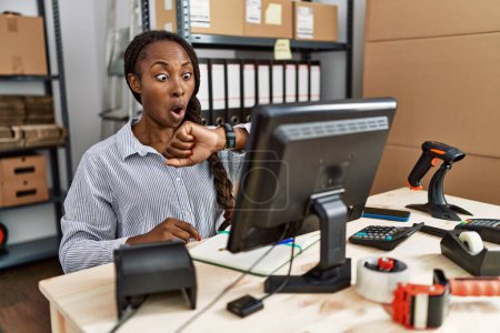 Foto de Mujer africana que trabaja en el comercio electrónico de pequeñas empresas mirando el tiempo reloj preocupado, miedo de llegar tarde - Imagen libre de derechos