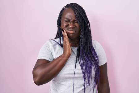 Photo for Young african woman standing over pink background touching mouth with hand with painful expression because of toothache or dental illness on teeth. dentist - Royalty Free Image