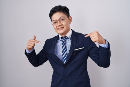 Photo for Young asian man wearing business suit and tie looking confident with smile on face, pointing oneself with fingers proud and happy. - Royalty Free Image
