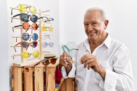Téléchargez les photos : Homme senior client tenant des lunettes au magasin de vêtements - en image libre de droit
