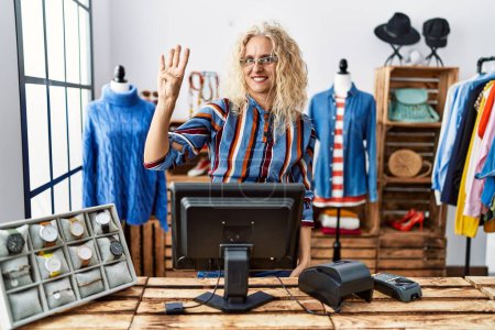 Photo for Middle age blonde woman working as manager at retail boutique showing and pointing up with fingers number four while smiling confident and happy. - Royalty Free Image
