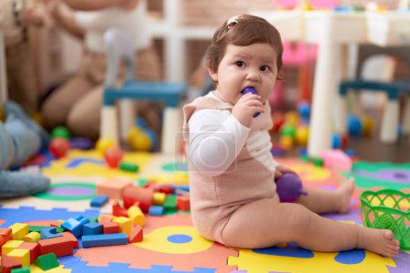 Téléchargez les photos : Adorable jouet alimentaire en plastique bitting pour tout-petit assis sur le sol à la maternelle - en image libre de droit