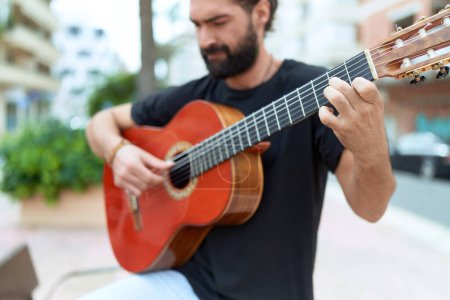 Téléchargez les photos : Young hispanic man musician playing classical guitar at park - en image libre de droit