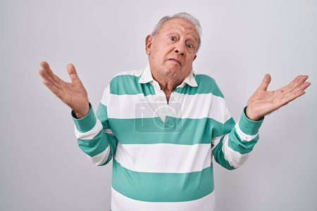 Photo for Senior man with grey hair standing over white background clueless and confused expression with arms and hands raised. doubt concept. - Royalty Free Image