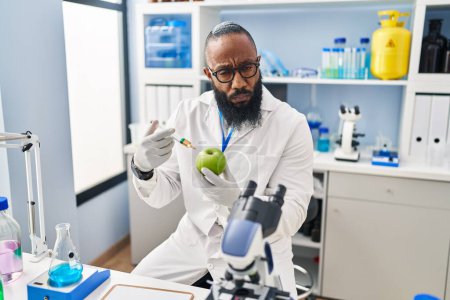 Téléchargez les photos : African american man working at scientist laboratory with apple depressed and worry for distress, crying angry and afraid. sad expression. - en image libre de droit