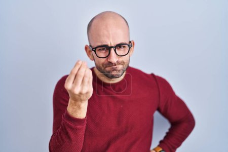 Téléchargez les photos : Young bald man with beard standing over white background wearing glasses doing italian gesture with hand and fingers confident expression - en image libre de droit