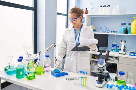 Téléchargez les photos : Young blonde woman wearing scientist uniform weighing test tube at laboratory - en image libre de droit