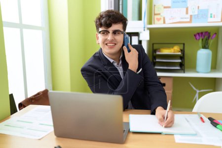 Téléchargez les photos : Non binary man business worker talking on smartphone writing on notebook at office - en image libre de droit