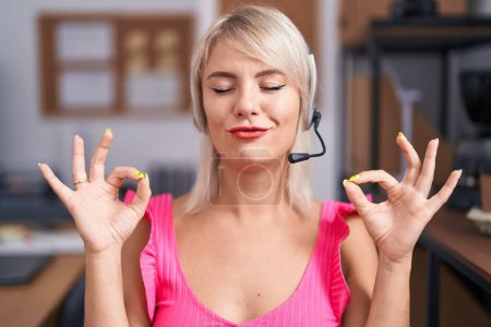 Foto de Young caucasian woman wearing call center agent headset relax and smiling with eyes closed doing meditation gesture with fingers. yoga concept. - Imagen libre de derechos