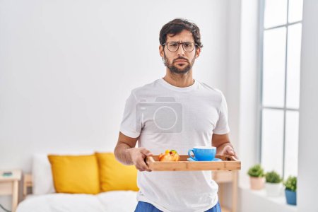Foto de Hombre latino guapo desayunando en la cama deprimido y preocupado por la angustia, llorando enojado y asustado. expresión triste. - Imagen libre de derechos