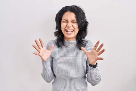 Photo for Hispanic woman with dark hair standing over isolated background celebrating mad and crazy for success with arms raised and closed eyes screaming excited. winner concept - Royalty Free Image