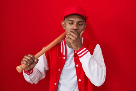 Foto de Young hispanic man playing baseball holding bat bored yawning tired covering mouth with hand. restless and sleepiness. - Imagen libre de derechos