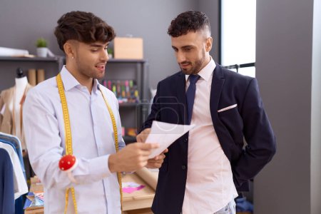 Téléchargez les photos : Two hispanic men tailor showing clothing design to client at atelier - en image libre de droit