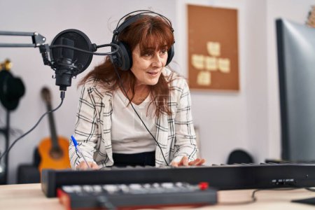 Téléchargez les photos : Middle age woman musician composing song at music studio - en image libre de droit