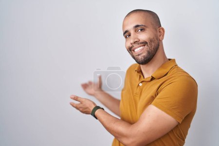Foto de Hispanic man with beard standing over white background inviting to enter smiling natural with open hand - Imagen libre de derechos