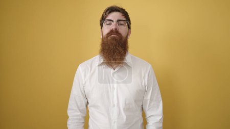 Foto de Young redhead man wearing glasses with relaxed expression over isolated yellow background - Imagen libre de derechos