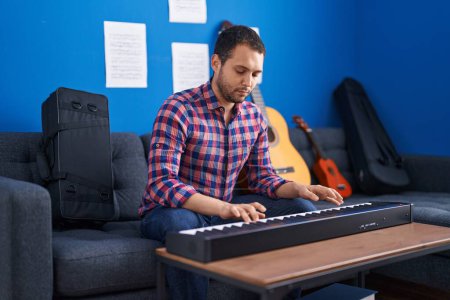 Téléchargez les photos : Young man musician playing piano keyboard at music studio - en image libre de droit