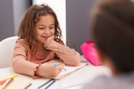 Téléchargez les photos : Two kids students sitting on table drawing on notebook paper at classroom - en image libre de droit