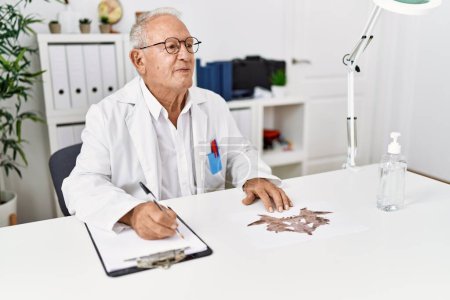 Téléchargez les photos : Homme âgé portant un uniforme de médecin faisant un test de rorscharch à la clinique - en image libre de droit