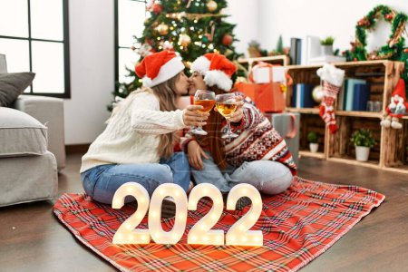 Téléchargez les photos : Femme couple baisers et toasts pour la nouvelle année 2022 assis par arbre de Noël à la maison - en image libre de droit