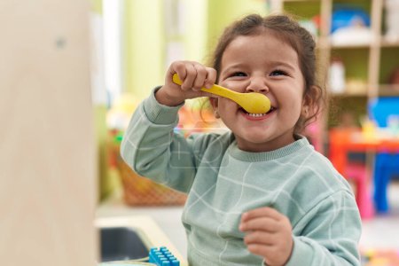 Téléchargez les photos : Adorable hispanic toddler playing with play kitchen standing at kindergarten - en image libre de droit