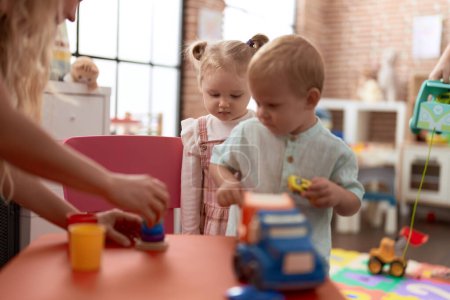 Foto de Adorable chica y niño jugando con juguetes en la mesa en el jardín de infantes - Imagen libre de derechos
