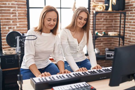 Téléchargez les photos : Two women musicians playing piano at music studio - en image libre de droit