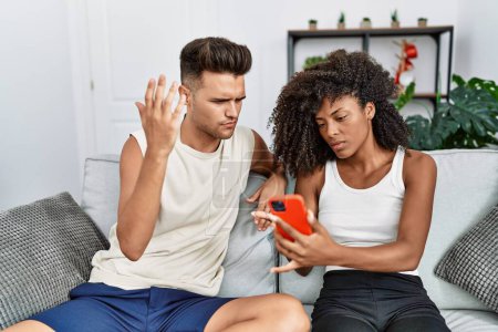 Téléchargez les photos : Couple homme et femme avec des problèmes d'utilisation du smartphone à la maison - en image libre de droit