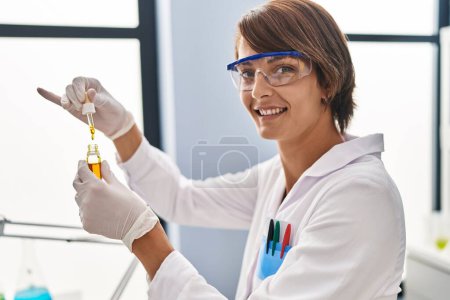 Téléchargez les photos : Jeune belle femme hispanique scientifique versant du liquide sur éprouvette au laboratoire - en image libre de droit