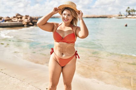Téléchargez les photos : Jeune femme hispanique portant un bikini et un chapeau d'été debout au bord de la mer - en image libre de droit