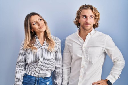 Photo for Young couple standing over blue background smiling looking to the side and staring away thinking. - Royalty Free Image