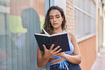 Téléchargez les photos : Jeune belle hispanique femme lecture livre à la rue - en image libre de droit