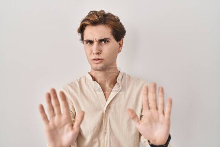 Photo for Young man standing over isolated background moving away hands palms showing refusal and denial with afraid and disgusting expression. stop and forbidden. - Royalty Free Image