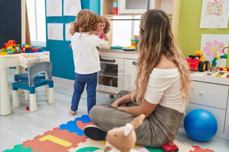 Photo for Teacher and toddler playing with play kitchen standing at kindergarten - Royalty Free Image